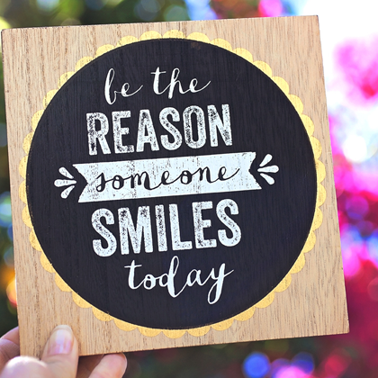 Random acts of kindness - person holding sign that says be the reason someone smiles today